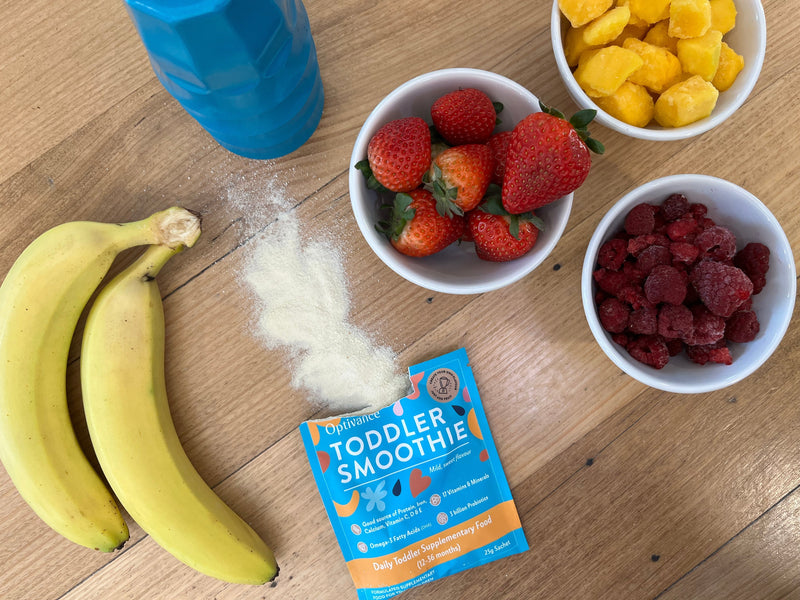 Mum and toddler looking at the nutrition information panel on an Optivance Toddler Smoothie box during a calm breakfast in a bright kitchen.